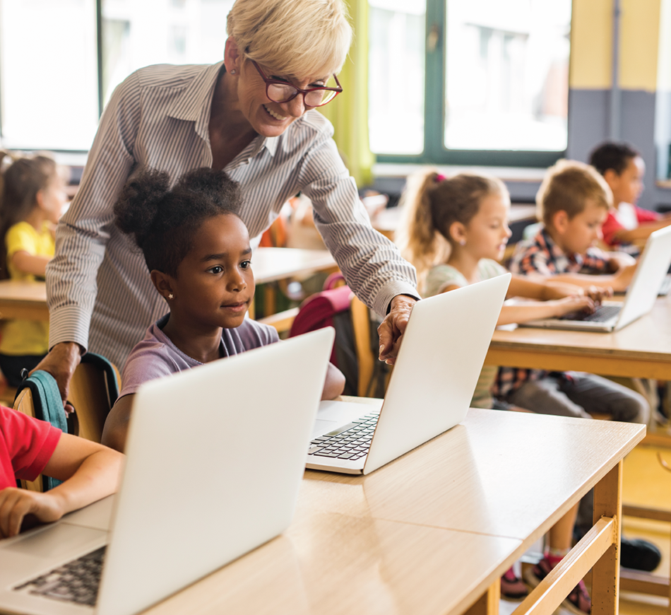 Little girl in front of a computer with teacher.