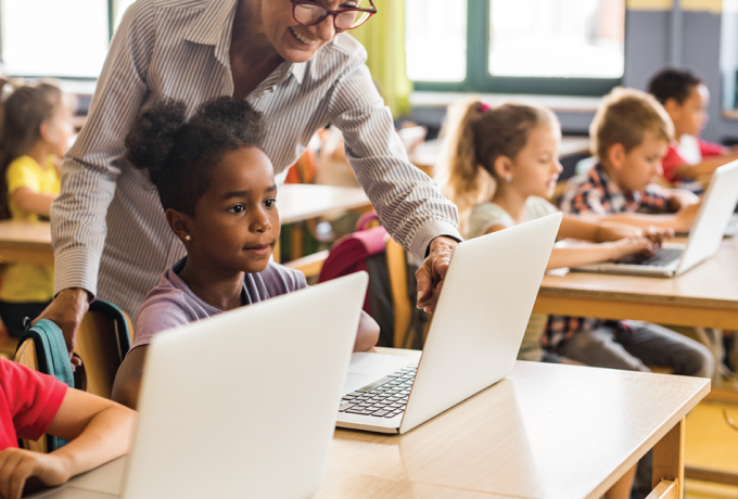 Little girl in front of a computer with teacher.